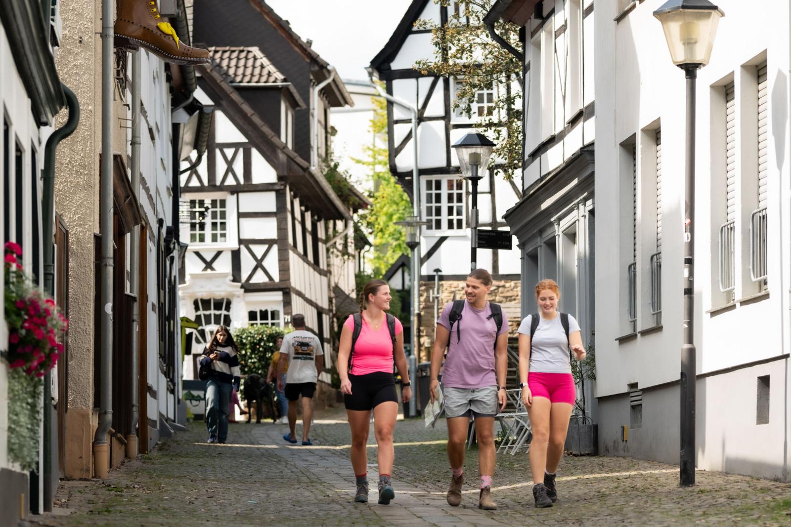 Wandelaars lopen door een straat met vakwerkhuizen in de Altstadt van Essen-Kettwig, Duitsland.