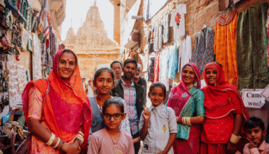 Lokale familie poseert in een smalle winkelstraat met kleurrijke kleding en tempels in Jaisalmer, India