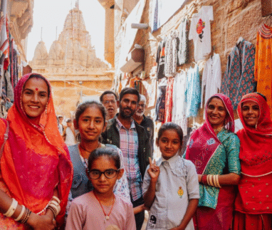 Lokale familie poseert in een smalle winkelstraat met kleurrijke kleding en tempels in Jaisalmer, India