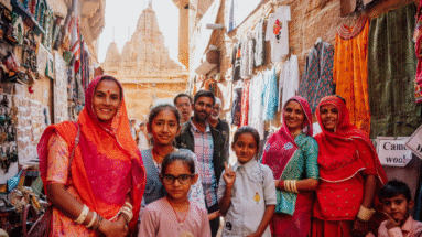 Lokale familie poseert in een smalle winkelstraat met kleurrijke kleding en tempels in Jaisalmer, India