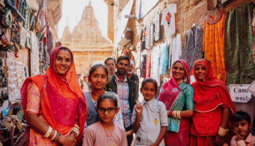 Lokale familie poseert in een smalle winkelstraat met kleurrijke kleding en tempels in Jaisalmer, India