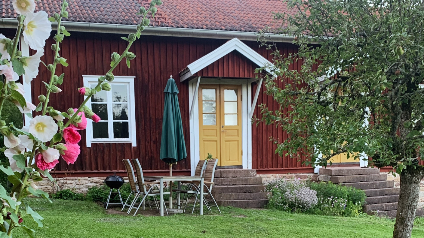 Rood houten Zweeds huisje met gele deur en tuin