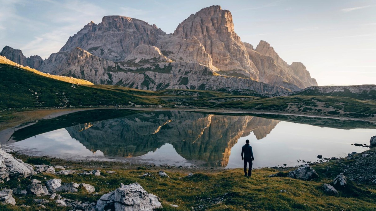 Wandelaar bij bergmeer met reflectie van rotsmassief in de Dolomieten, Italië