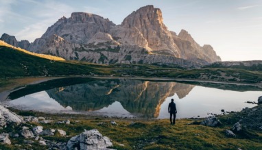 Wandelaar bij bergmeer met reflectie van rotsmassief in de Dolomieten, Italië