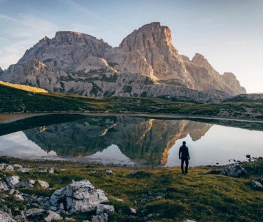 Wandelaar bij bergmeer met reflectie van rotsmassief in de Dolomieten, Italië