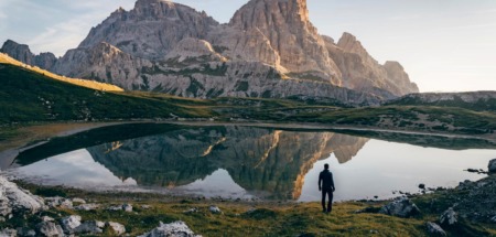 Wandelaar bij bergmeer met reflectie van rotsmassief in de Dolomieten, Italië