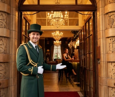 Hotelconcierge verwelkomt gast bij de deur
