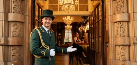 Hotelconcierge verwelkomt gast bij de deur