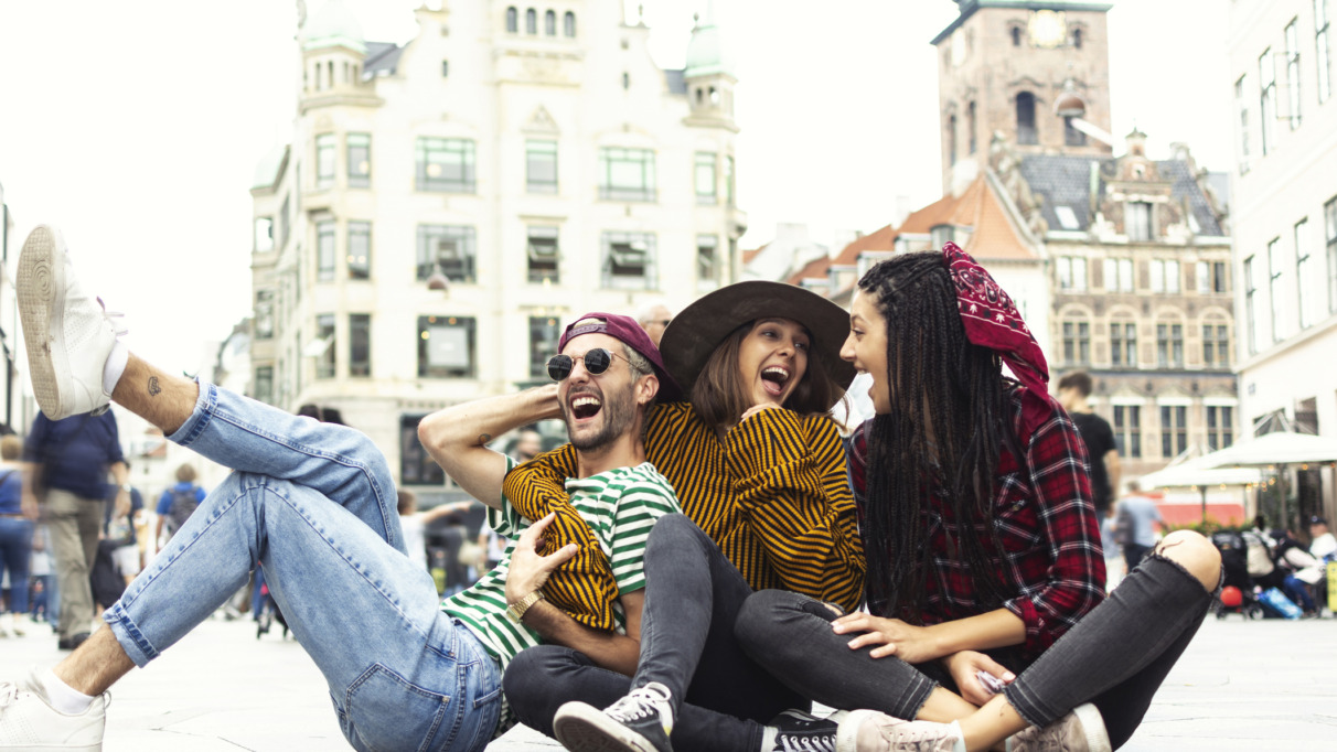 Die vrolijke vrienden liggen lachend op straat in Kopenhagen, Denemarken, de hoofdstad van geluk