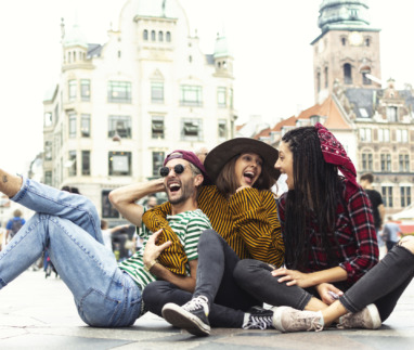 Die vrolijke vrienden liggen lachend op straat in Kopenhagen, Denemarken, de hoofdstad van geluk