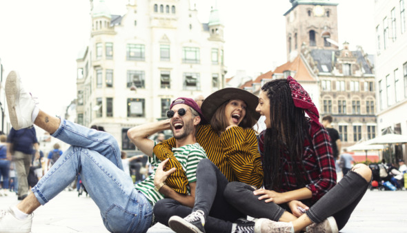 Die vrolijke vrienden liggen lachend op straat in Kopenhagen, Denemarken, de hoofdstad van geluk