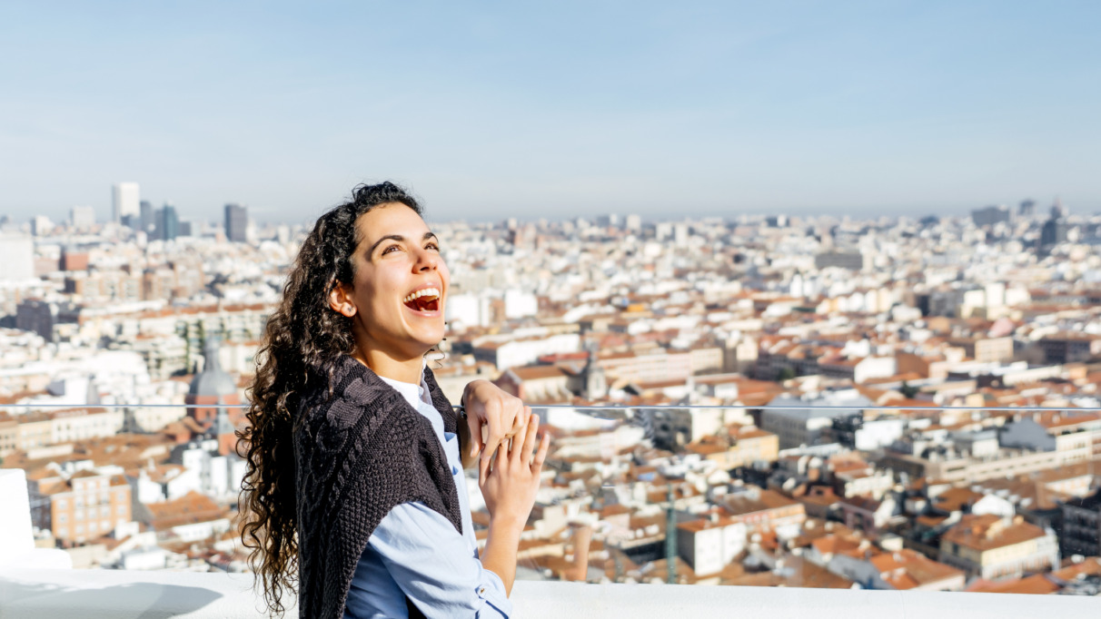 Vrouw staat te lachen boven de skyline van Madrid in Spanje
