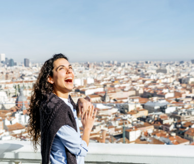 Vrouw staat te lachen boven de skyline van Madrid in Spanje