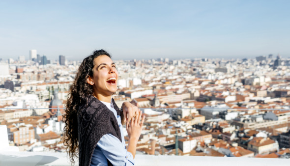 Vrouw staat te lachen boven de skyline van Madrid in Spanje