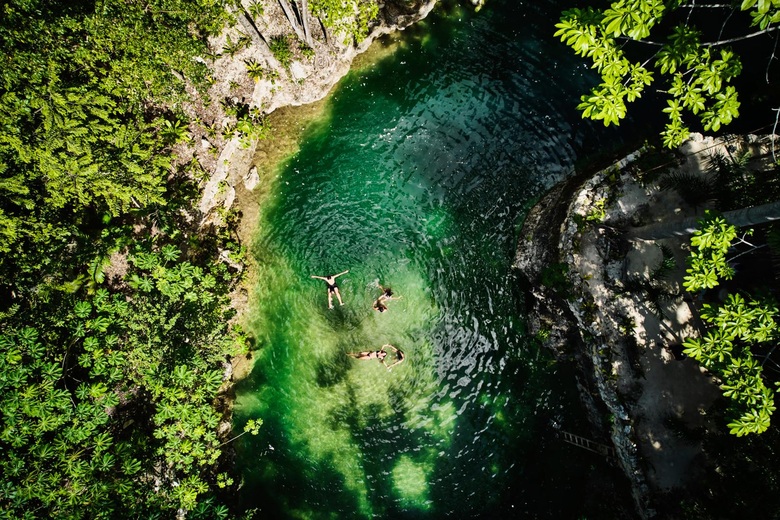 Zwemmers in een cenote omringd door tropische jungle op het schiereiland Yucatán in Mexico.