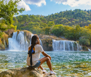 Jonge vrouw kijkt uit over Krka watervallen in Kroatië