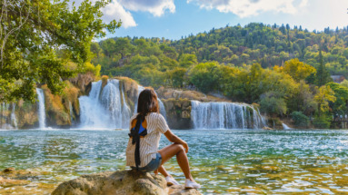 Jonge vrouw kijkt uit over Krka watervallen in Kroatië