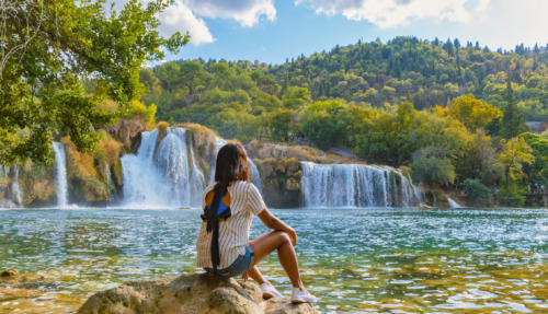 Jonge vrouw kijkt uit over Krka watervallen in Kroatië