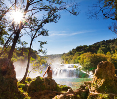 Jonge vrouw kijkt uit over Krka watervallen in Kroatië