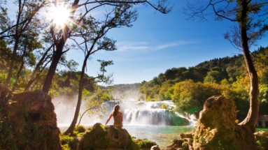Jonge vrouw kijkt uit over Krka watervallen in Kroatië