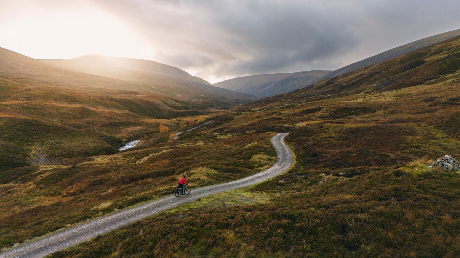 Mountainbiker op een slingerend pad in de Schotse Hooglanden bij zonsondergang.