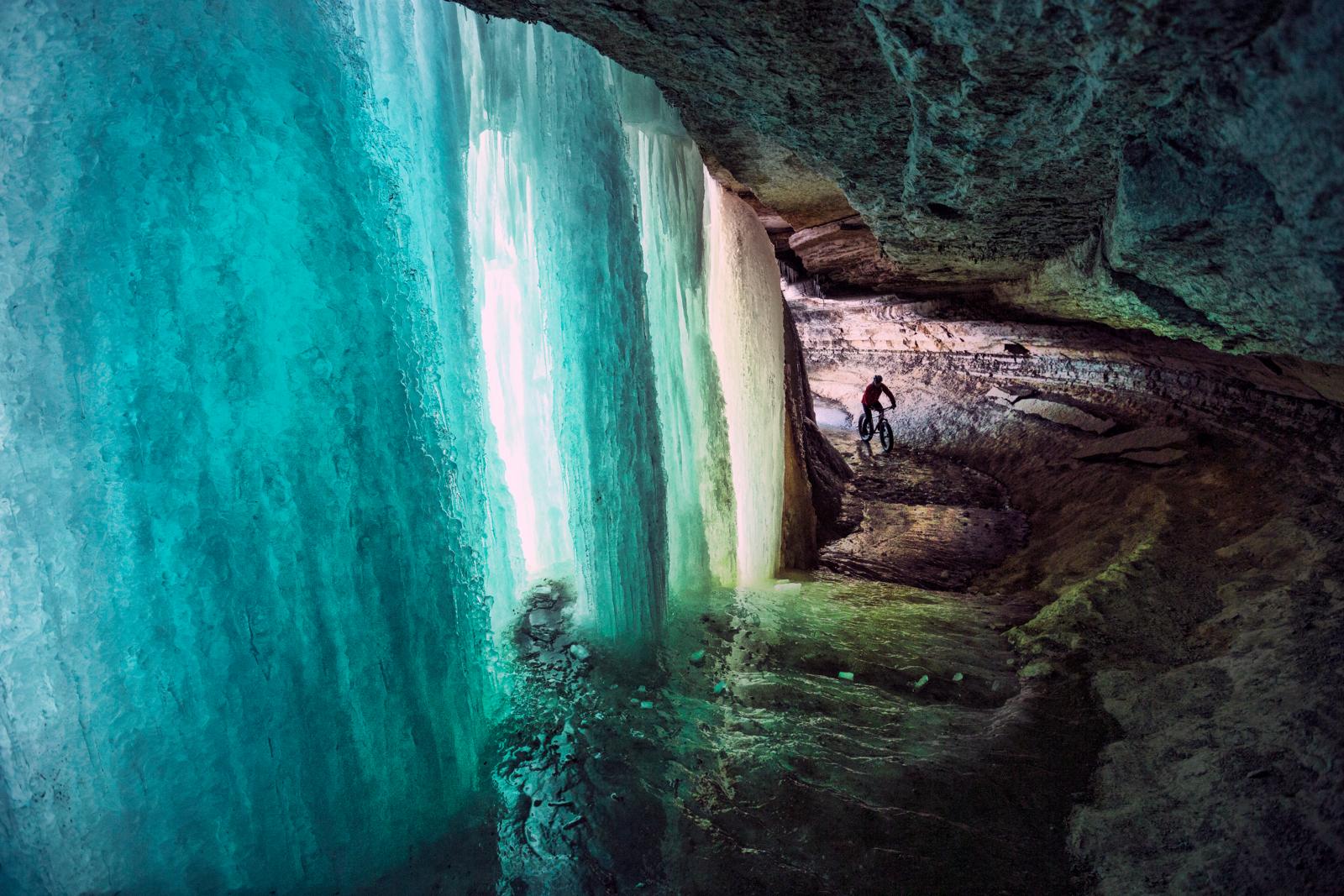 Mountainbiker in een ijsgrot met een bevroren waterval.