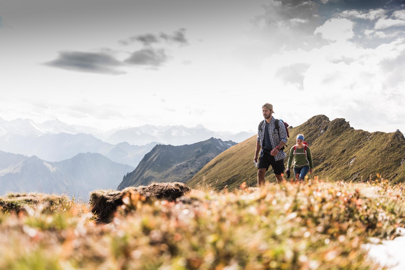 Twee wandelaars op een bergkam in de Allgäu Alpen met uitzicht op gelaagde bergtoppen.