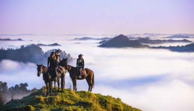 groep ruiters op een berg kijkt uit over laaghangende bewolking