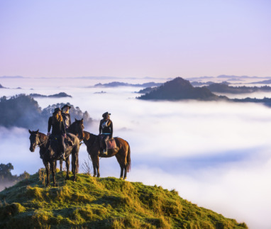 groep ruiters op een berg kijkt uit over laaghangende bewolking