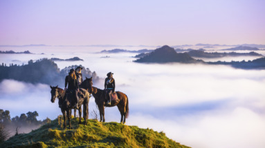 groep ruiters op een berg kijkt uit over laaghangende bewolking