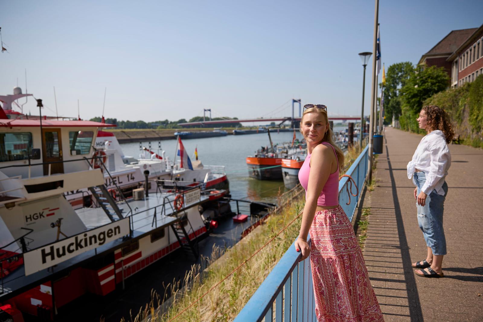 Bezoekers langs de kade in de havenwijk Ruhrort in Duisburg met schepen op de Rijn.