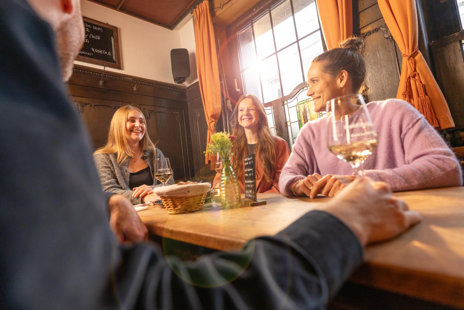 Vrienden drinken wijn en praten in een gezellige, traditionele Weinstube in Mainz, Duitsland