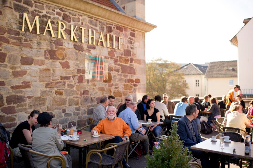 Bezoekers zitten op het terras bij de Markthalle in Kassel, Duitsland