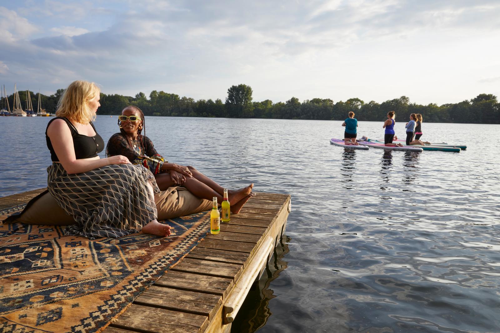 Mensen ontspannen aan het water van de Sechs-Seen-Platte in Duisburg terwijl anderen suppen.