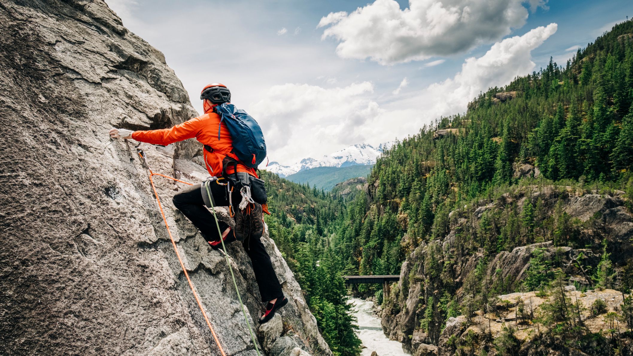 Rotsklimmer op een granieten wand boven een beboste vallei bij Squamish in British Columbia, Canada.