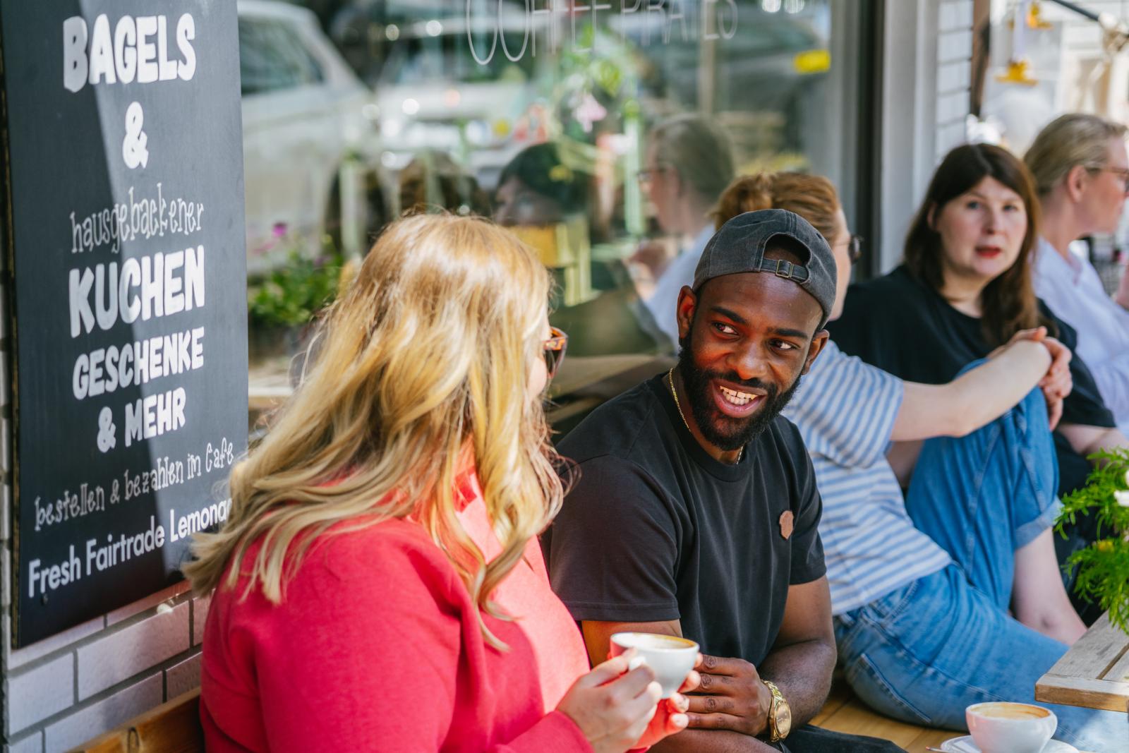 Mensen drinken koffie op een terras in de levendige wijk Rüttenscheid in Essen, Duitsland.