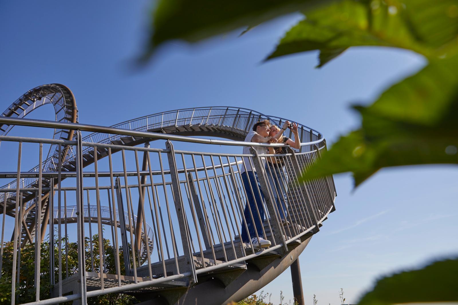 Stel op de Tiger & Turtle wandelbrug in Duisburg dat een foto maakt op de stalen constructie.