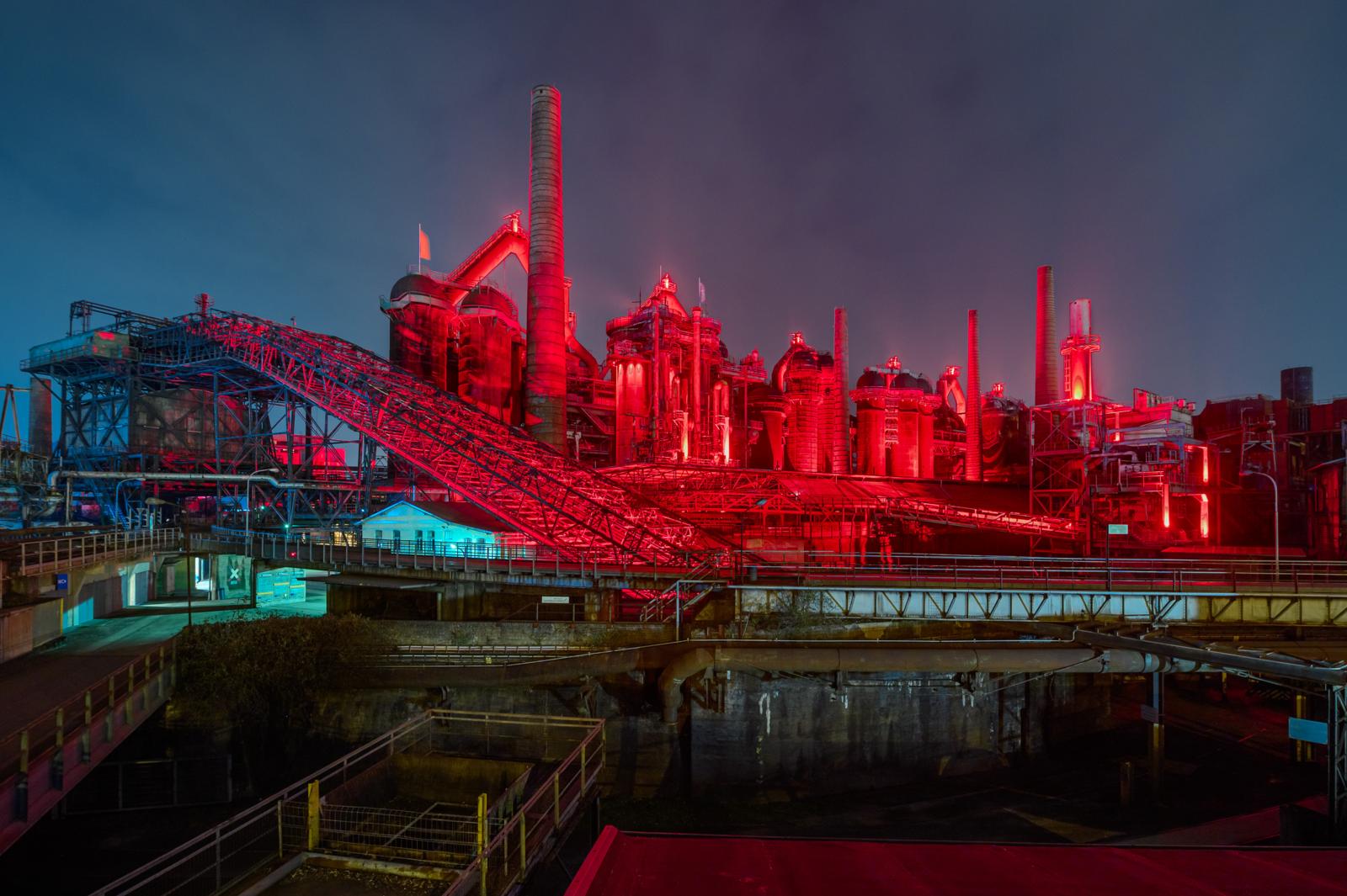 Industrieterrein van de Völklinger Hütte verlicht in rood licht in de avond in Duitsland
