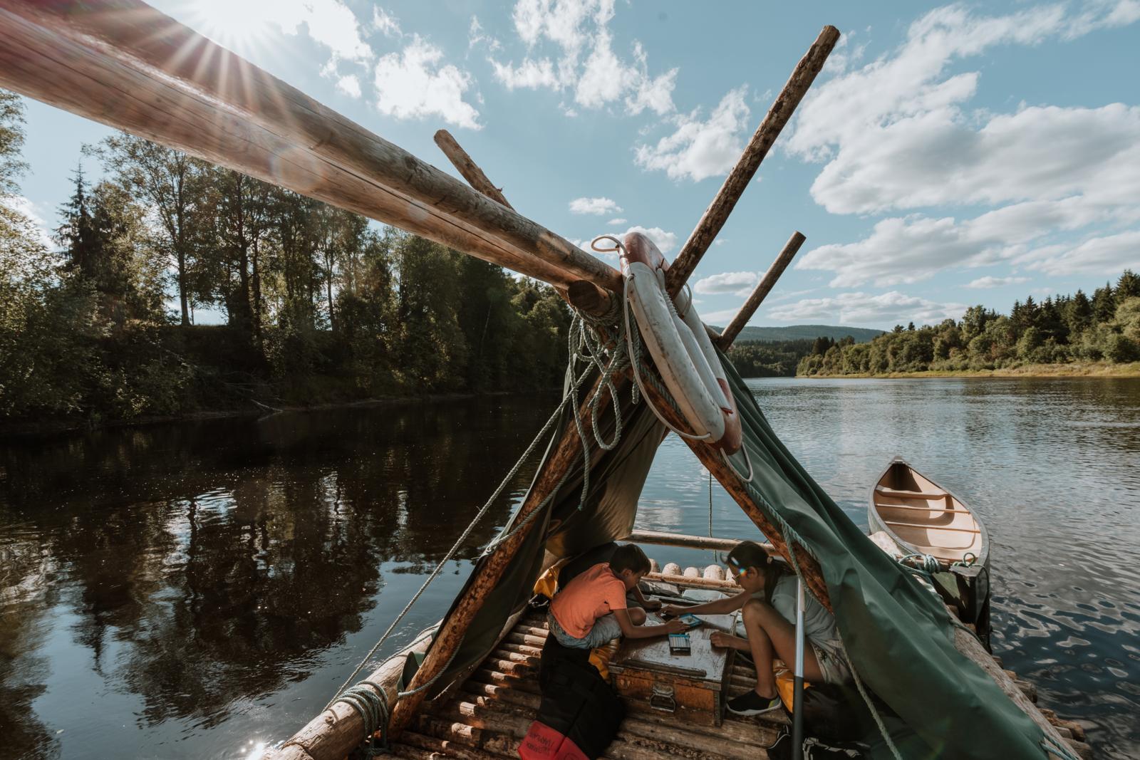 Twee kinderen spelen op een zelfgemaakt houtvlot op de Klarälven in Värmland