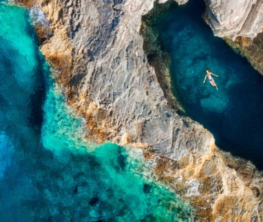 Vrouw drijft in inham of grot van de zee in Kroatië