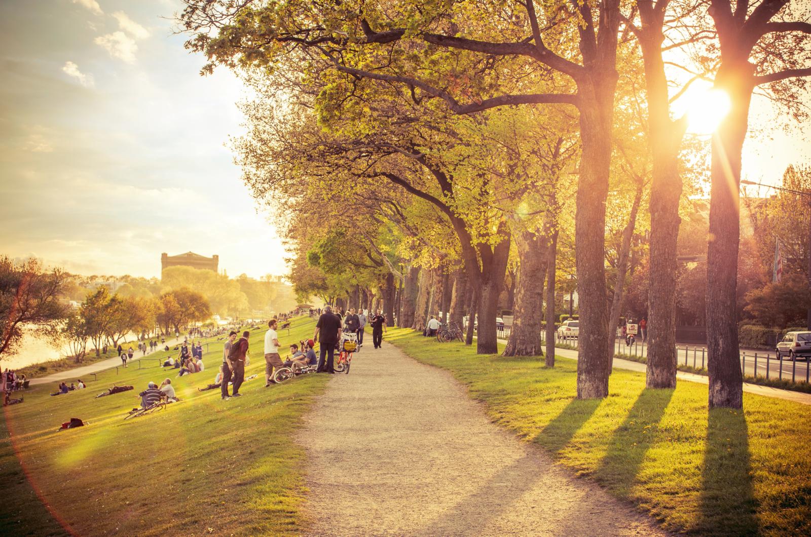 Mensen wandelen en ontspannen langs de Osterdeich in Bremen bij zonsondergang.