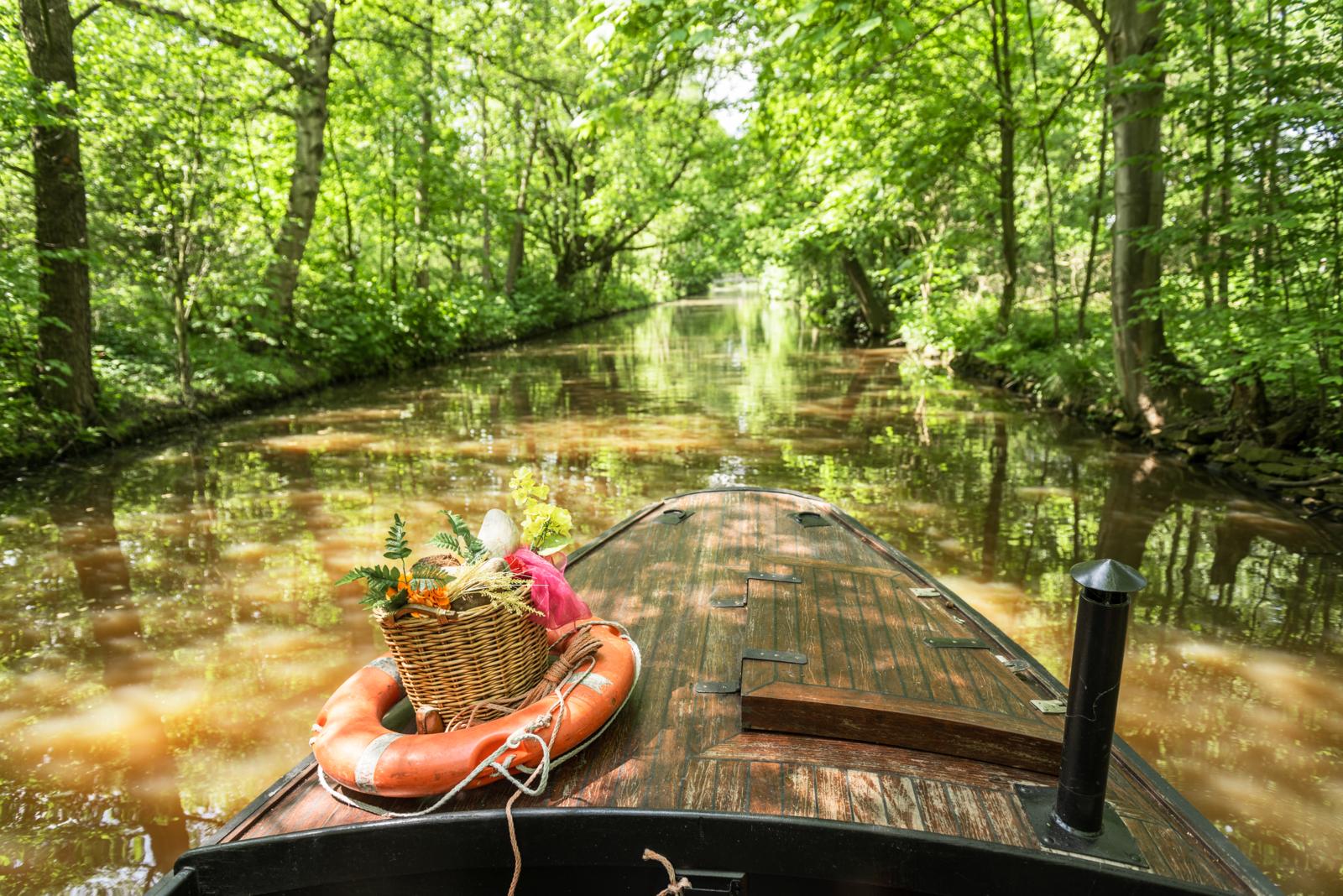 Houten boot met picknickmand vaart door smalle watergang in het Teufelsmoor bij Bremen.