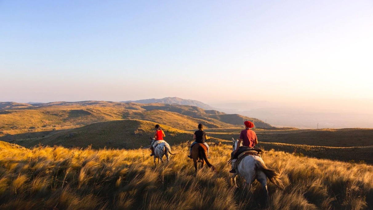 Ruiters te paard trekken door het berglandschap van de Balkan bij zonsondergang.