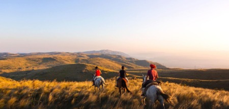Ruiters te paard trekken door het berglandschap van de Balkan bij zonsondergang.