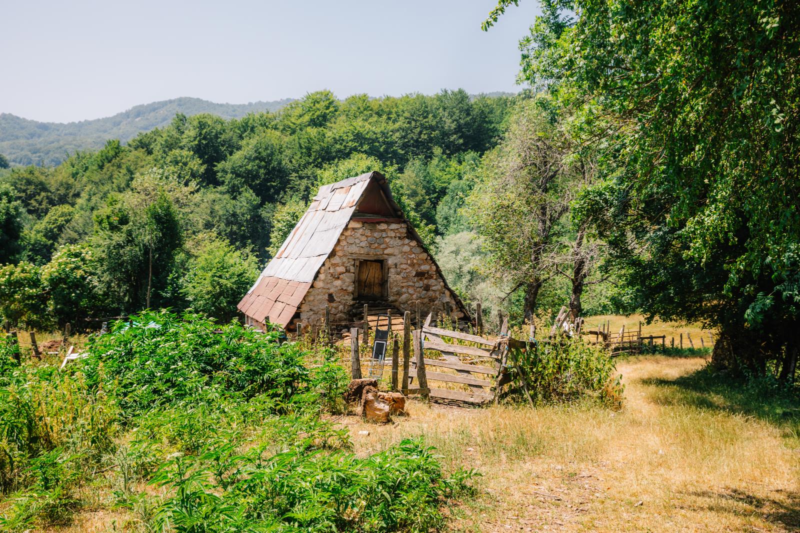 stenen berghuisje met puntdak in groene heuvels van Bosnië en Herzegovina