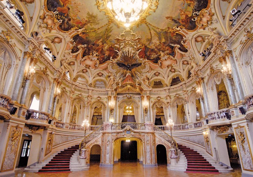 Een weelderige goudversierde zaal met een indrukwekkend beschilderd plafond en dubbele trap in Wiesbaden.
