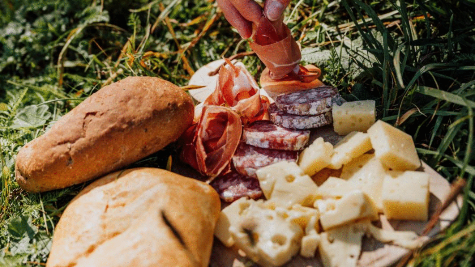 brood, kaas en vleeswaren op plank tijdens picknick in gras in Trentino