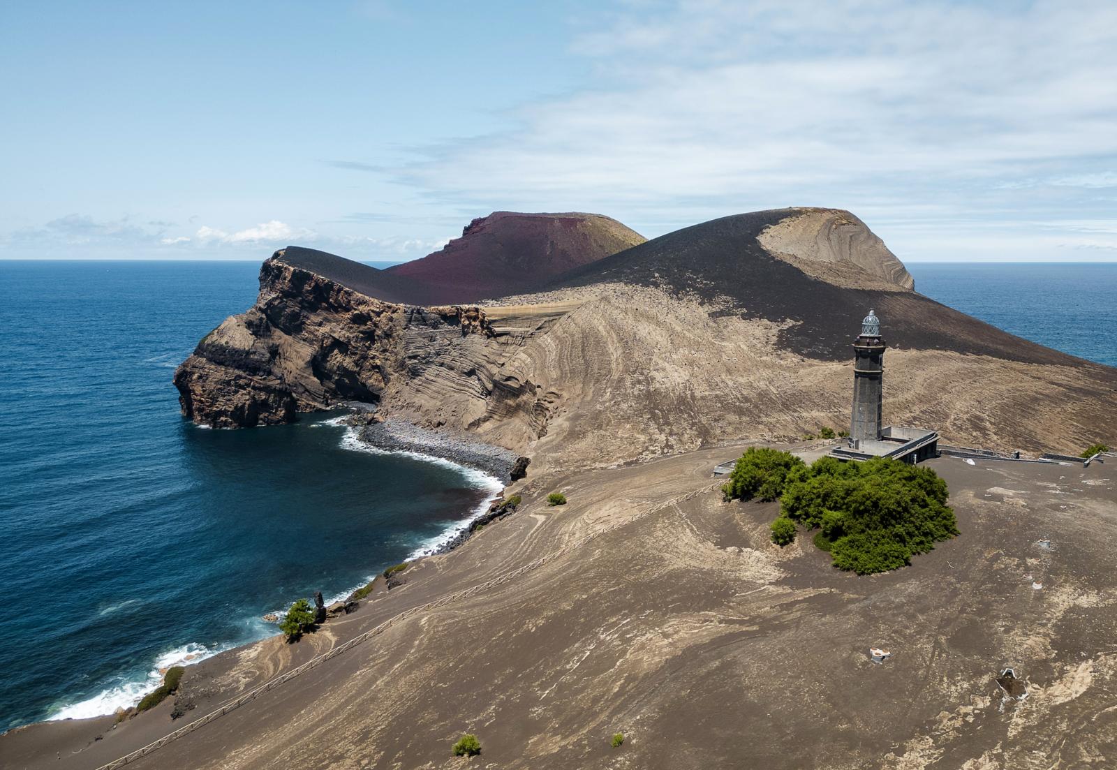 vuurtoren bij de vulkaan Capelinhos op Faial met zwart lavalandschap en Atlantische oceaan, Azoren
