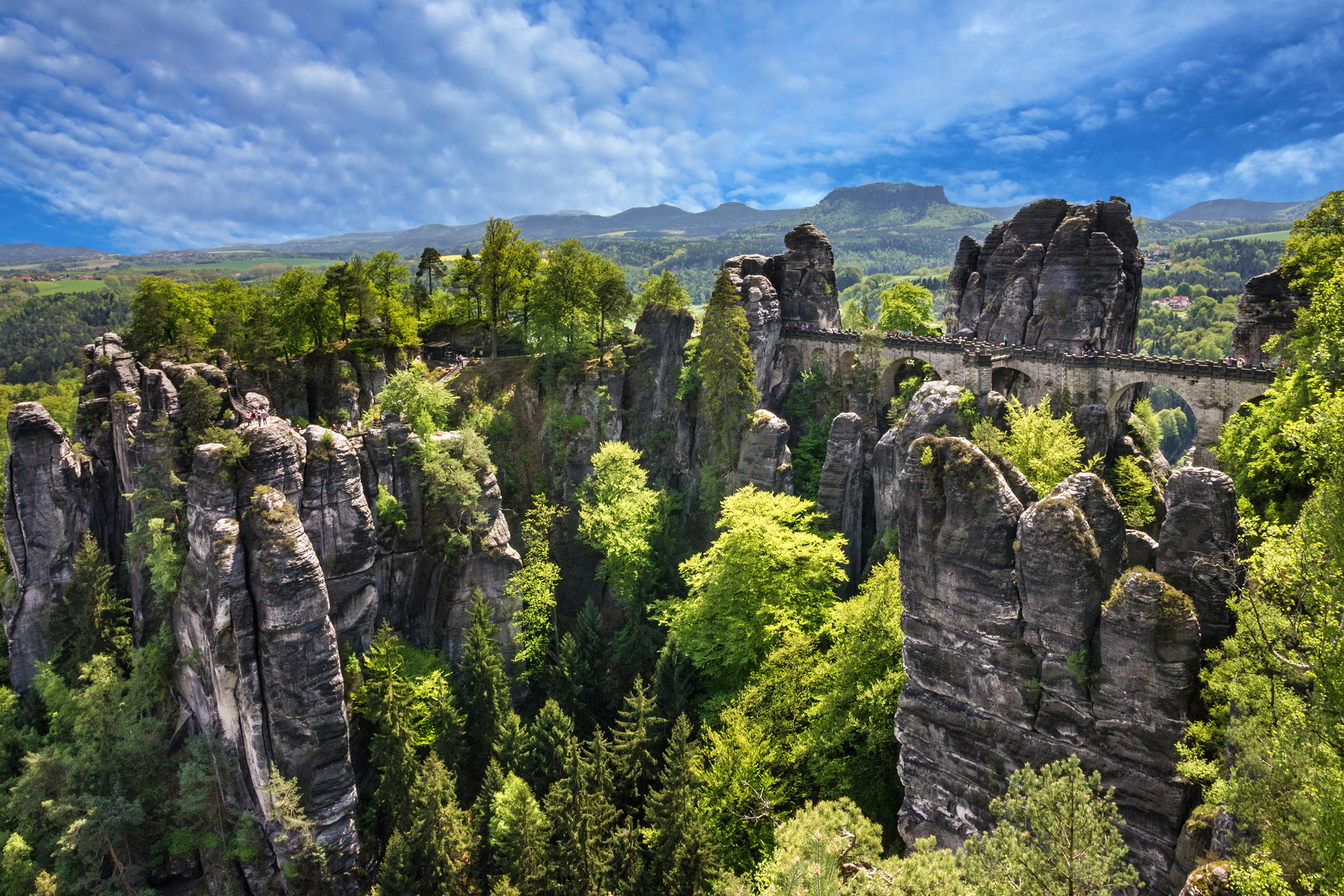 ontdek de Malerweg in het Elbezandsteengebergte. Tijdens de tweede etappe steek je de beroemde Basteibrücke over. Deze stenen brug slingert tussen de verticale rotsformaties door en biedt een duizelingwekkend uitzicht op de Elbe die diep beneden je stroomt. 