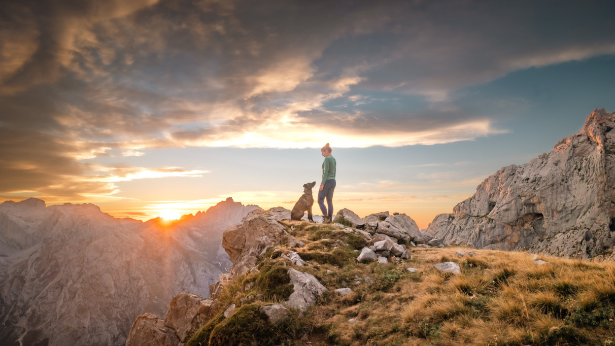Vrouw loopt met hond door Picos de Europa, het eerste nationale park van Spanje